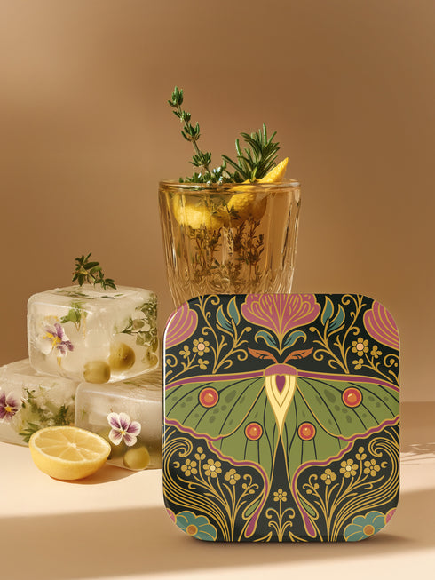 A set of four square hardboard coasters with smoothly rounded corners and a protective high-gloss finish. Each coaster features a unique, highly detailed Art Nouveau style illustration of a moth centered against a dark, botanical background. The intricate artwork uses a rich, moody color palette of deep forest greens, ochre, muted olive, crimson, and black, evoking a vintage, scholarly feel. These decorative drinkware accessories are designed for coffee table and bar cart use.
